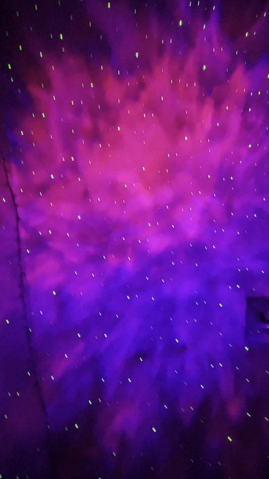 Pink and purple nebula with green laser stars projected on a ceiling