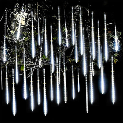 Falling rain tube lights hanging through a garden shrub at night