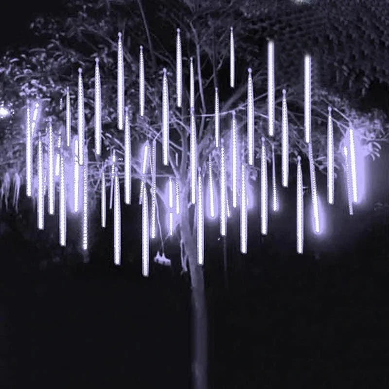 Tree hung with falling rain tube lights at night
