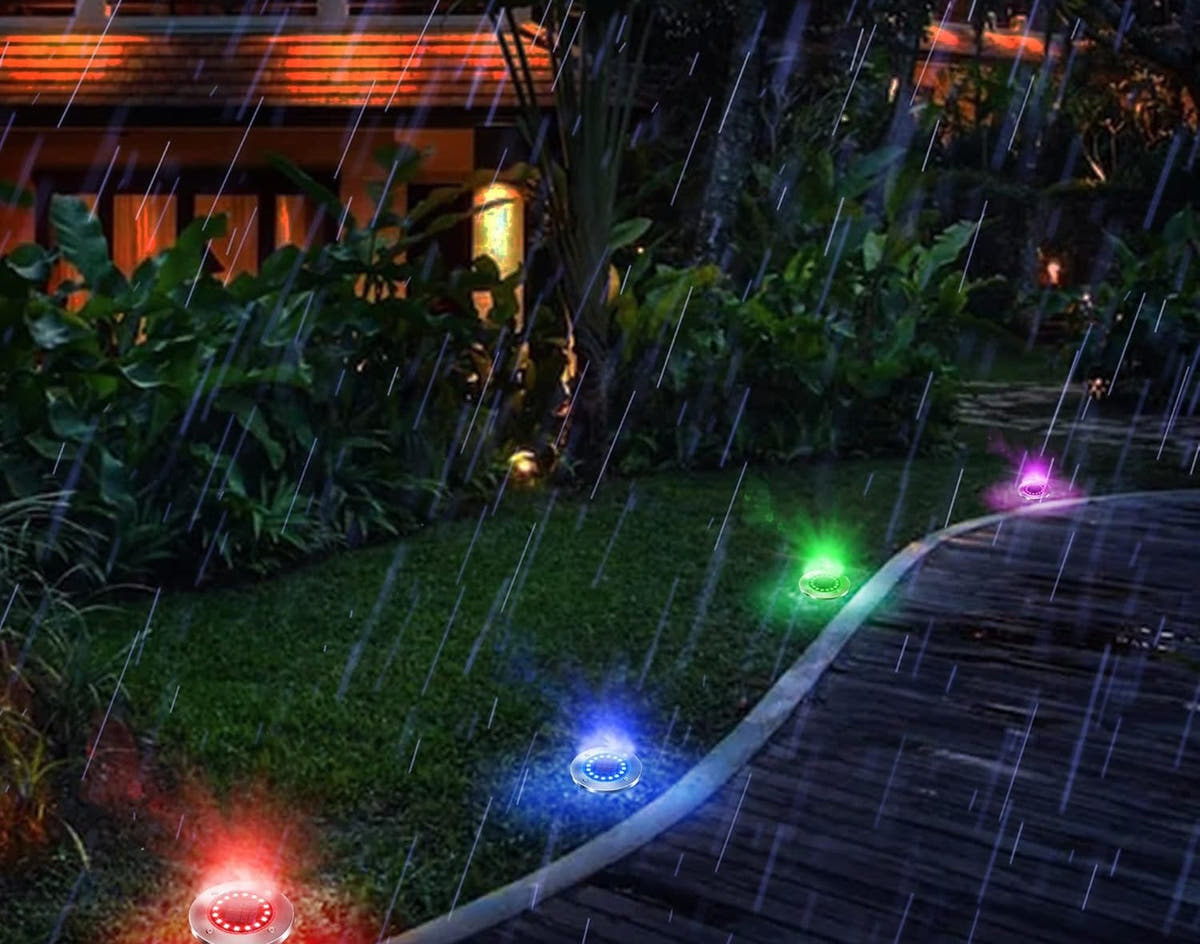 Solar disk lights tracing a garden path edge at night, colour-changing