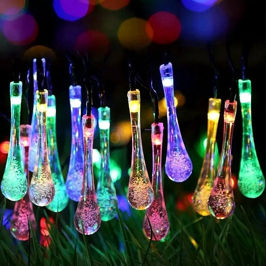 Multi-colour raindrop bubble lights glowing over a garden at night