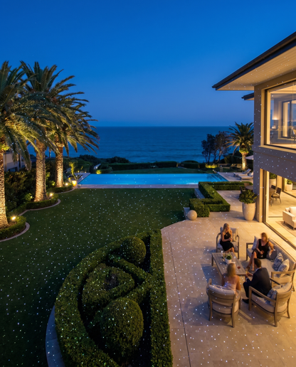Coastal estate with infinity pool, lawn covered in white laser star points at night